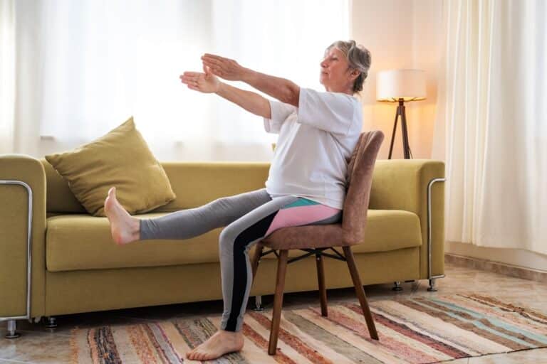 Senior,Caucasian,Woman,Doing,Yoga,At,Home,On,Chair